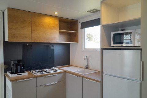 Moderne keuken in Verblijfpark Breebos 4, België, met houten kasten, gasfornuis en magnetron.
