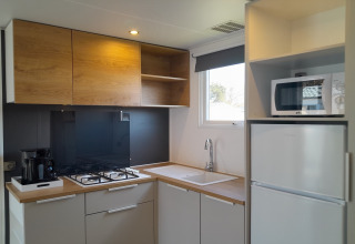 Moderne keuken in Verblijfpark Breebos 4, België, met houten kasten, gasfornuis en magnetron.