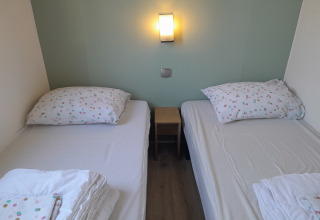 Twee eenpersoonsbedden met wit beddengoed en stippenkussens in een kamer van Verblijfpark Breebos 4, België.