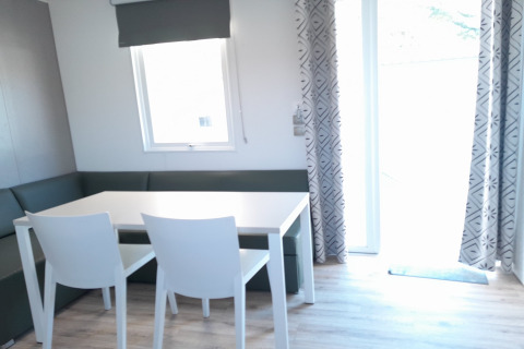 Zona pranzo con tavolo bianco, due sedie e panca angolare presso il lodge Verblijfpark Breebos 4, Belgio