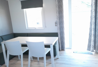 Eethoek met witte tafel, twee stoelen en hoekbank in Verblijfpark Breebos 4 lodge, België, licht interieur