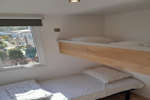Kamer met stapelbedden en twee bedden aan het raam in Verblijfpark Breebos 4 in België, zonlicht schijnt binnen.
