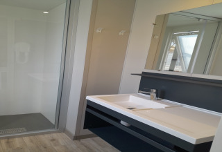 Moderne badkamer in Verblijfpark Breebos 4, België, met douche, wastafel en een grote spiegel.