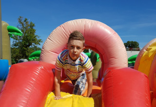 Jongen speelt op kleurrijk springkussenparcours bij Verblijfpark Breebos 4 in België onder een blauwe lucht.