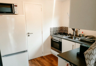 Moderne Küche im Chalet «Chocolat» in Belgien mit Herd, Backofen, Spüle, Kühlschrank und Mikrowelle.