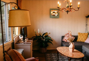 Acogedora sala de estar del Chalet «Chocolat» en Bélgica con lámparas vintage y plantas de interior.