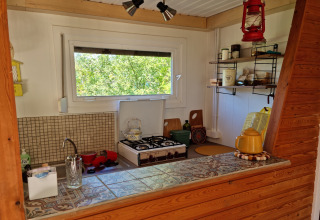 Acogedora cocina pequeña en el chalet Casita La Luna en Bélgica, con ventana y estufa de gas.