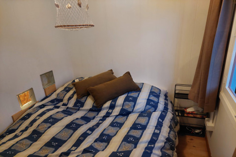 Dormitorio en chalet Casita La Luna en Bélgica con cama doble, cojines marrones y ventana con cortina.