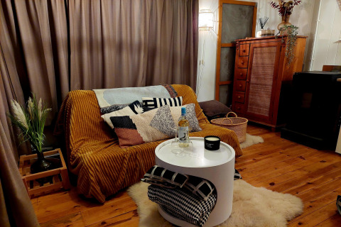 Acogedora sala de estar en el chalet Casita La Luna en Bélgica, con sofá, manta y copa de vino.