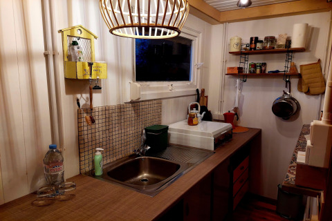 Acogedora cocina de Casita La Luna en Bélgica, con encimera de madera y estantes organizados.
