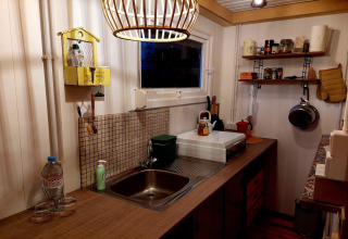 Acogedora cocina de Casita La Luna en Bélgica, con encimera de madera y estantes organizados.