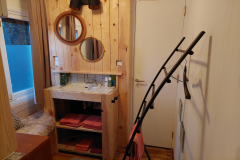 Baño acogedor con paredes de madera, espejos redondos y lavabo en Casita La Luna, Bélgica.
