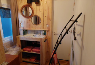 Baño acogedor con paredes de madera, espejos redondos y lavabo en Casita La Luna, Bélgica.