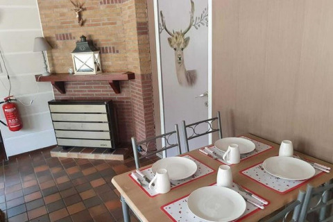 Salle à manger du lodge The Deer Forest en Belgique, table dressée, cheminée et porte à motif de cerf.
