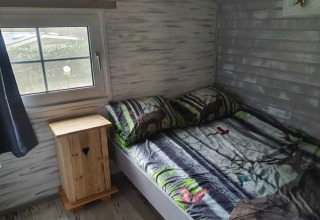 Cozy bedroom in The Deer Forest lodge in Belgium with woodland decor and deer-themed bedding and pillows.
