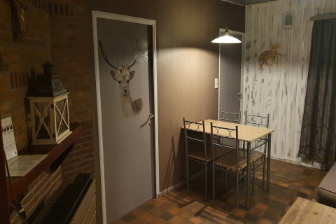 Zona pranzo alla lodge The Deer Forest in Belgio con porta cervo, tavolo, sedie e decorazioni.