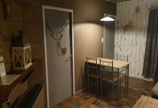 Zona pranzo alla lodge The Deer Forest in Belgio con porta cervo, tavolo, sedie e decorazioni.