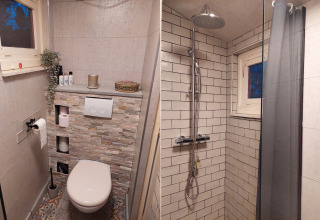Baño en Casita La Luna, Bélgica, con inodoro moderno, nichos de almacenamiento y ducha con azulejos.