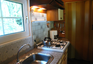 Cuisine chaleureuse de la cabane The Deer Forest en Belgique avec gazinière, évier et ustensiles.