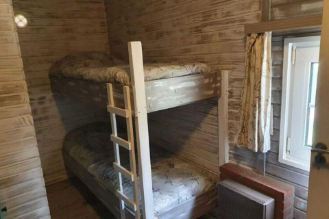 Stanza accogliente al lodge The Deer Forest in Belgio con letto a castello, pareti in legno e finestra piccola.