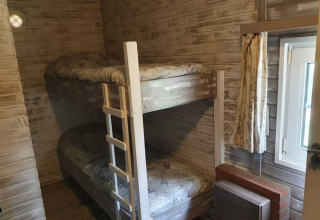 Et hyggeligt værelse i The Deer Forest lodge i Belgien med køjesenge, trævægge og et lille vindue.