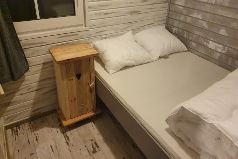 Chambre confortable au lodge The Deer Forest en Belgique avec murs en bois, lit et table de nuit en bois.