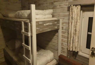 Une chambre avec des lits superposés et des murs en bois clair à la lodge «The Deer Forest» en Belgique.