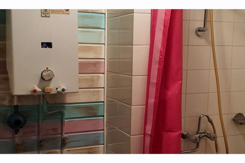 Badkamer in The Deer Forest lodge in België met een douche, waterverwarmer en roze douchegordijn.