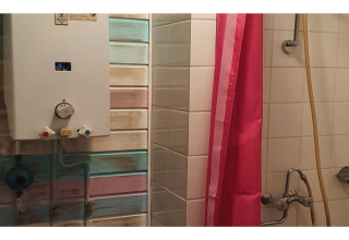 Bathroom at The Deer Forest lodge in Belgium showing a shower, water heater, and pink shower curtain.