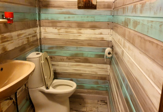 Badkamer met houten panelen, toilet en wc-papier in The Deer Forest Lodge in België.