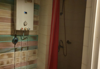 Water heater and shower with a red curtain in the bathroom at The Deer Forest Lodge in Belgium.
