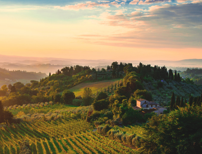 Heuvels en wijngaarden rond Siena, Toscane, Italië bij zonsondergang, met een huis omringd door groen.