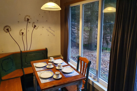 Comedor en la cabaña 'Forest House the Squirrel' en Bélgica con vista al bosque a través de grandes ventanas.