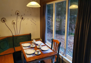 Angolo pranzo al lodge 'Forest House the Squirrel' in Belgio con vista sul bosco da grandi finestre.