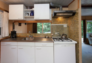 Cucina compatta in Forest House the Squirrel, Belgio, con fornello, lavello e mobili bianchi luminosi.