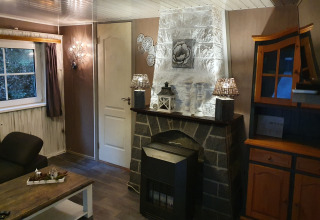 Acogedora sala en Forest House the Squirrel, Bélgica, con chimenea de piedra y luz cálida decorativa.