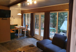 Soggiorno nel Forest House the Squirrel in Belgio, con divano, angolo pranzo e grandi finestre sul bosco.