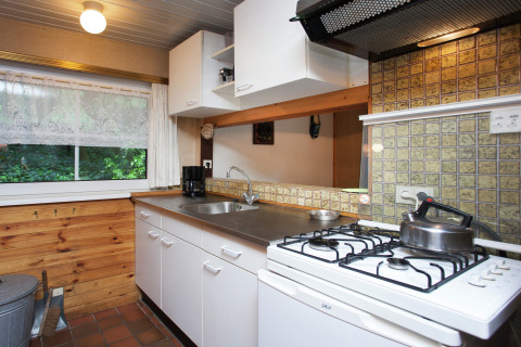 Acogedora cocina en Forest House the Squirrel en Bélgica con estufa de gas, fregadero y vista al bosque.