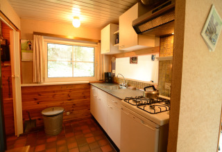 Acogedora cocina de Forest House the Squirrel en Bélgica, con revestimiento de madera y cocina de gas.
