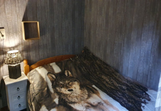 Camera accogliente in Forest House the Squirrel, Belgio, con copripiumino di lupo e arredo rustico.