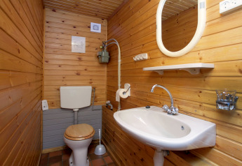 Piccolo bagno rustico con pareti in legno, WC, lavandino e specchio al Forest House the Squirrel in Belgio.