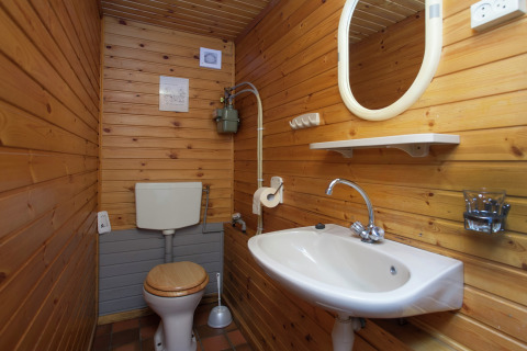 Pequeño baño rústico con paredes de madera, inodoro, lavabo y espejo en Forest House the Squirrel, Bélgica.