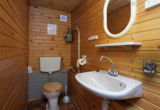 Pequeño baño rústico con paredes de madera, inodoro, lavabo y espejo en Forest House the Squirrel, Bélgica.