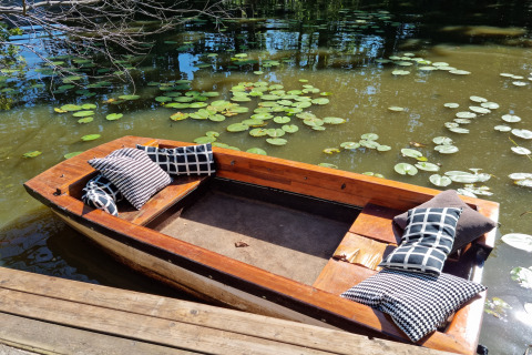 Barca de madera con cojines en un estanque de nenúfares junto a la cabaña 'Casita La Luna' en Bélgica.