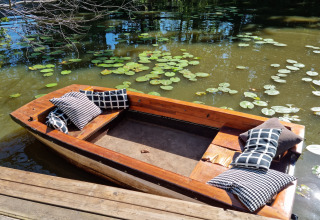 Barca de madera con cojines en un estanque de nenúfares junto a la cabaña 'Casita La Luna' en Bélgica.