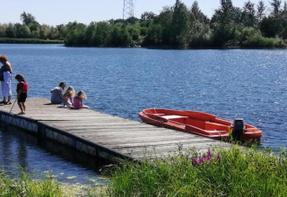Famille se détend sur un ponton en bois avec un bateau rouge à Forest House the Squirrel en Belgique.