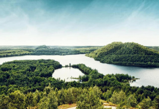 Vista de colinas boscosas y río desde la cabaña Forest House the Squirrel en Bélgica bajo cielo despejado.