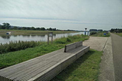 Un banc en bois près d'une rivière, le long d'un chemin dans un site de glamping verdoyant.