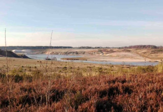 Uitzicht op een natuurlandschap en vijver vanuit een glampingverblijf in de buitenlucht.