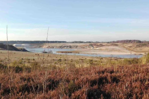 Vista de un paisaje natural con lago y campo desde un alojamiento de glamping al aire libre.